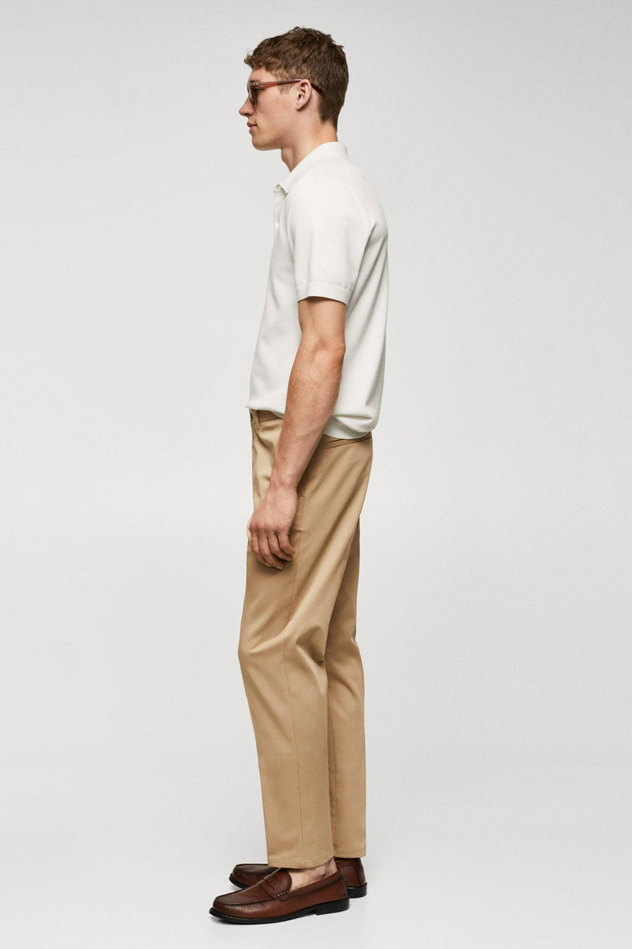 Pantalon chino marron de MANGO, vu de l'arrière, associé à un polo blanc et des loafers en cuir marron.