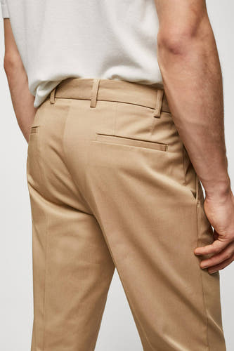 Jean chino marron de MANGO, avec poche arrière et passants, porté avec un T-shirt blanc.