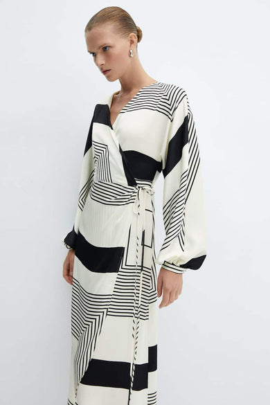 Manteau beige à longues manches de MANGO, avec imprimé géométrique noir et ceinture à la taille.