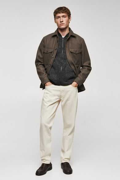Gilet gris de MANGO, porté avec un pull marron et un pantalon crème.