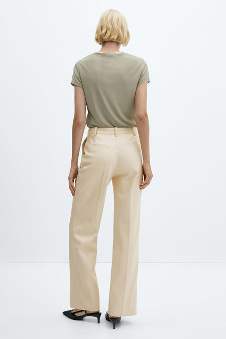 Pantalon large beige de MANGO, dos avec poches, modèle portant un chemisier vert et des talons noirs