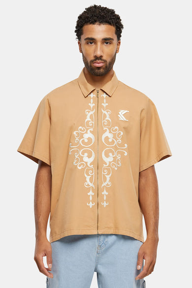 Chemise beige à manches courtes de Karl Kani, avec une broderie verticale et un col italien.