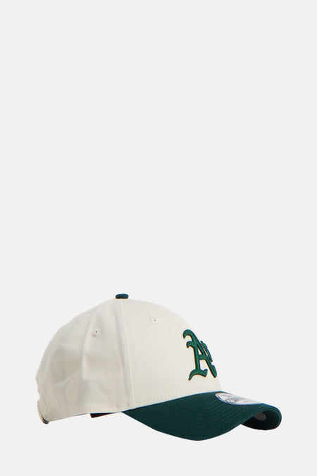 Chapeau beige de NEW ERA, avec une languette verte foncée et des détails du logo brodés.