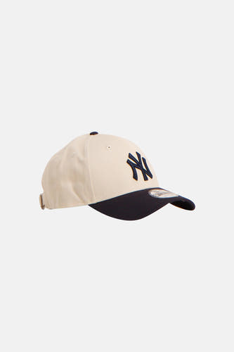 Casquette beige de NEW ERA avec visière bleu foncé et logo sur le devant.