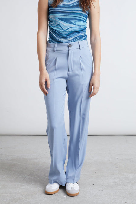 Pantalon bleu de 24 couleurs, avec des plis à l'avant et associé à un chemise rayée.