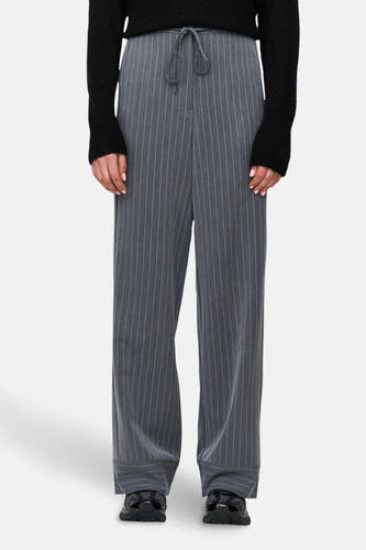 Pantalon gris de 24 colours gmbh avec une ceinture en tissu et un cordon, associé à une chemise noire et des chaussures.