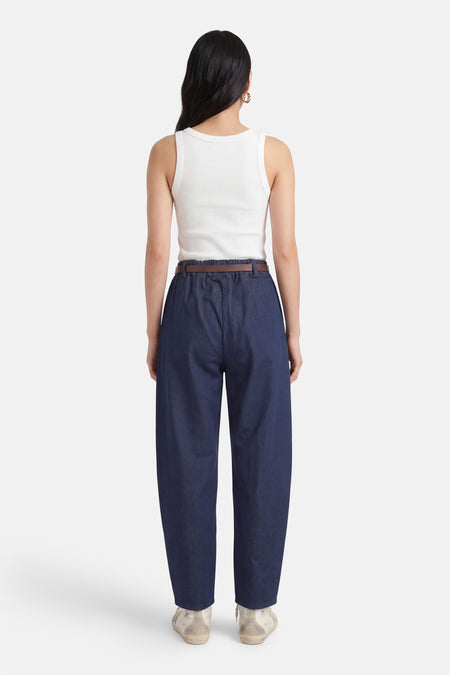 Mom jeans bleu foncé de Terra di Siena, avec une ceinture et des chaussures marron foncé.