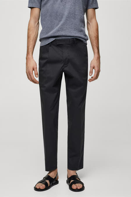 Pantalon de costume bleu marine de MANGO, avec une fermeture à glissière et des boutons et une texture lisse.