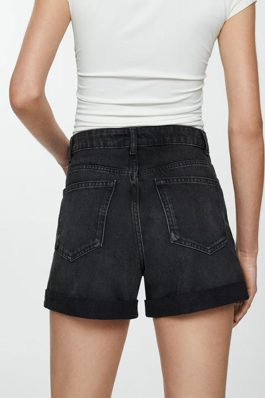 Short de denim noir de MANGO, vu de de l'arrière avec des poches rabattues, associé à un t-shirt blanc.