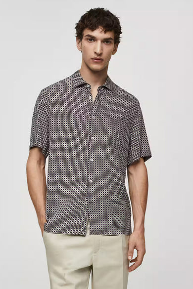 Chemise bleue à manches courtes de MANGO, avec un motif géométrique et une fermeture à boutons.