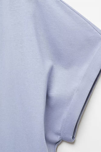T-shirt bleu de MANGO, gros plan sur un tissu côtelé avec une manche retroussée.