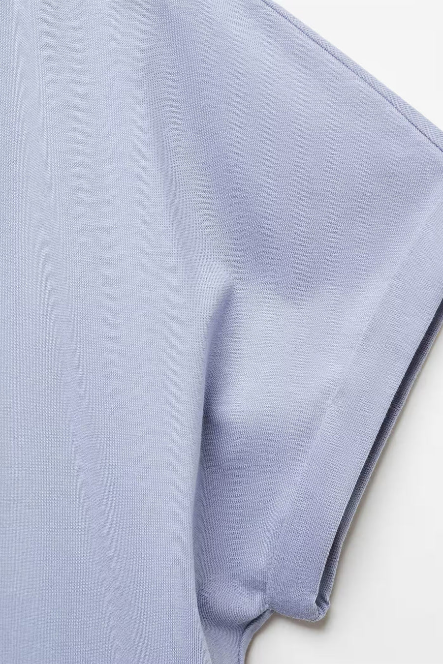 T-shirt bleu de MANGO, gros plan sur un tissu côtelé avec une manche retroussée.