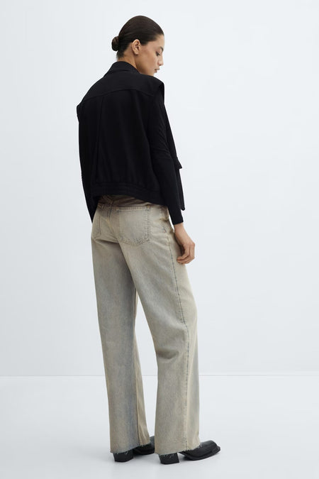 Jean ample en denim délavé de MANGO avec un ourlet brut, porté par un mannequin vu de dos.
