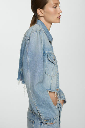 Jean en denim bleu marine de MANGO, avec une coupe courte et des détails froncés, en vue latérale.