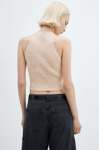 Sous-vêtement rose de MANGO, avec une texture côtelée et un col haut, associé à un pantalon noir avec ceinture.