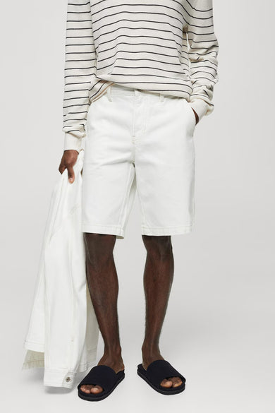 Short de denim blanc de MANGO, associé à un pull rayé et des pantoufles noires.