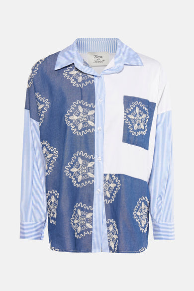 Chemise bleue à longues manches de Terra di Siena, avec des motifs floraux blancs sur le dos et des manches rayées.