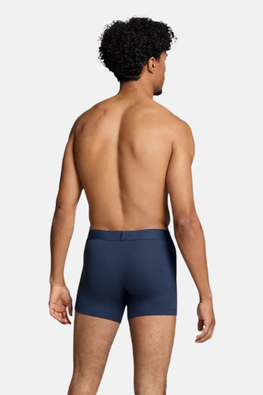 Man met ontbloot bovenlichaam, blauwe boxershort, achterkant.