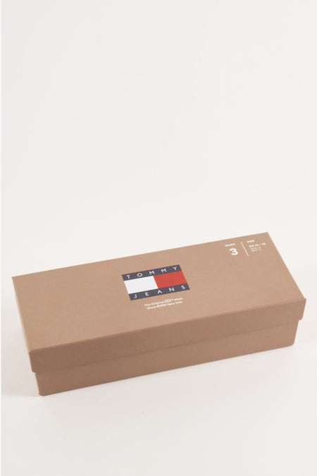 Sacs cadeaux bleus de TOMMY JEANS, emballés dans une boîte brune avec logo et informations sur le matériau.