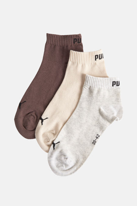 Chaussettes brunes de PUMA, avec logo sur le côté et emballage contenant des informations sur la taille.