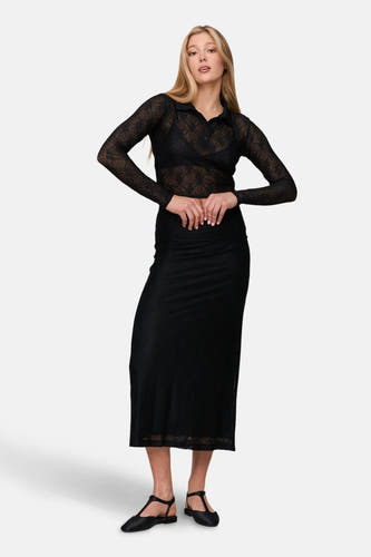 Robe noire de 24 Colours GmbH, avec un motif géométrique transparent, combinée à une blouse noire transparent et des chaussures noires.