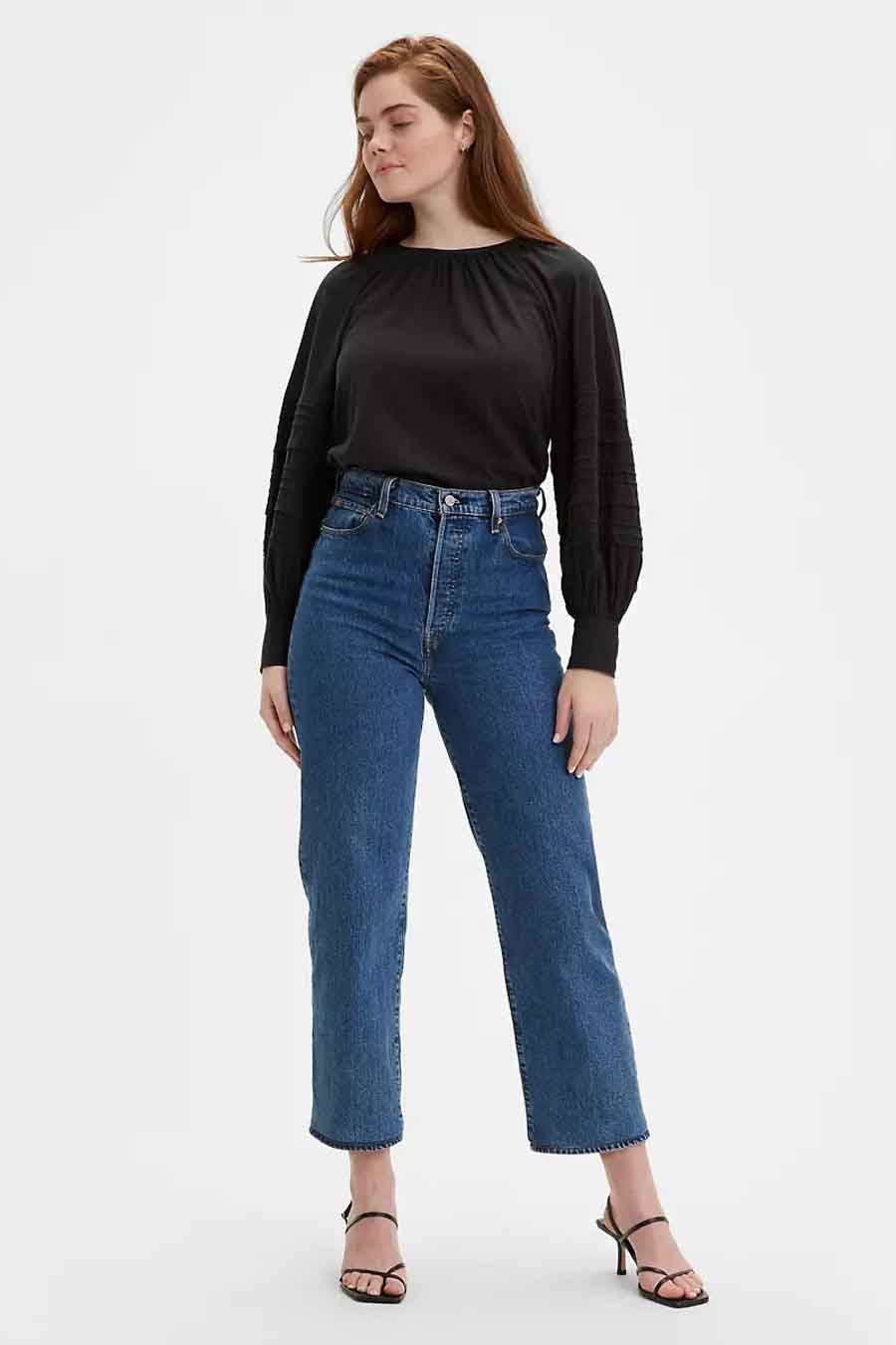 Jean droit en denim bleu moyen de Levi's, associé à un chemisier noir et des talons.