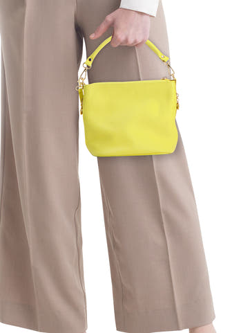 Sac à bandoulière jaune Access® en matière texturée, avec poignée courte et ferrures dorées, porté par une personne.