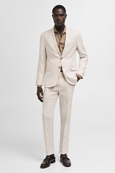 Man in crèmekleurig linnen pak met bruine schoenen.