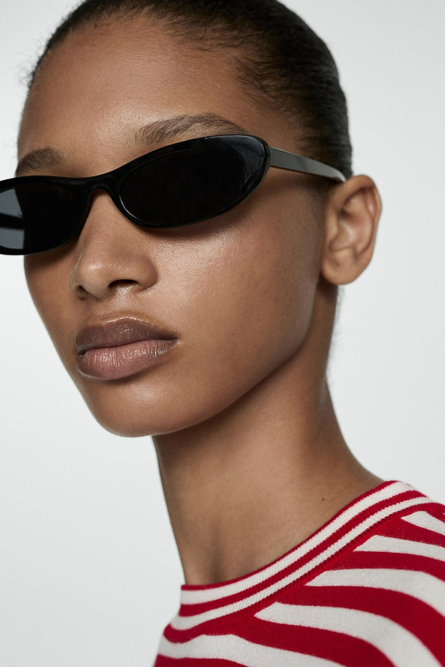 Vrouw met zonnebril, rood-wit gestreepte trui.