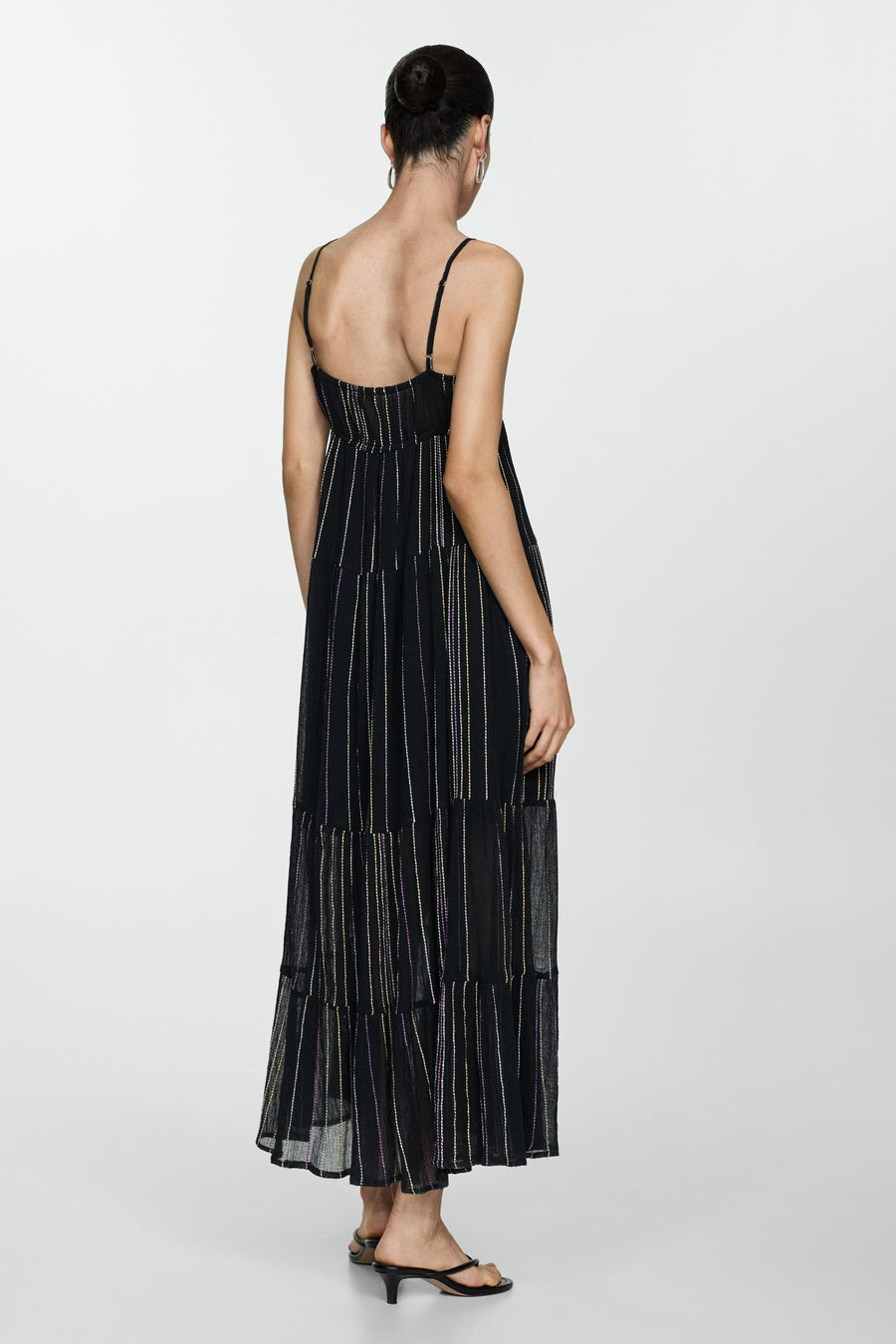 Achterkant van een model in een lange zwarte jurk met spaghettibandjes.