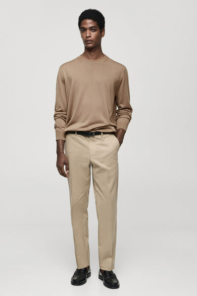 Pull marron avec col rond de MANGO, à longues manches, associé à un pantalon beige, une ceinture et des chaussures noires.