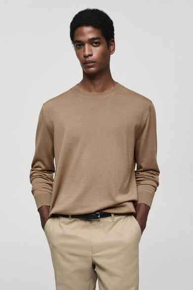 Pull marron avec col rond de MANGO, porté avec un pantalon kaki et une ceinture noire.