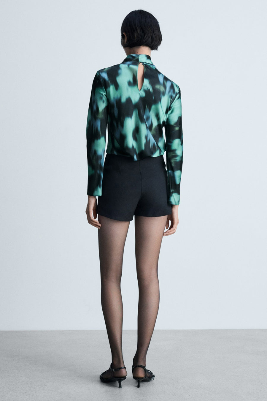 Blouse multicolore à longues manches de MANGO, avec une impression abstraite bleue et verte et une ouverture à l'arrière.