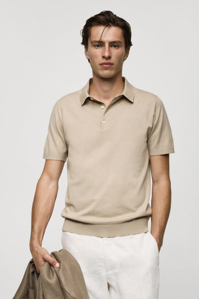 Polo beige à manches courtes de MANGO, tissu lisse, fermeture classique à boutons, modèle en pose lifestyle avec pantalon blanc