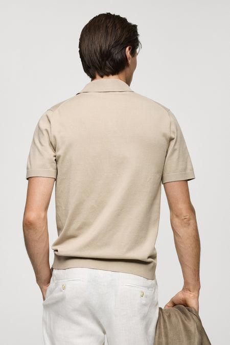 Polo beige à manches courtes de MANGO, vue de dos, tissu lisse, le modèle porte un pantalon blanc
