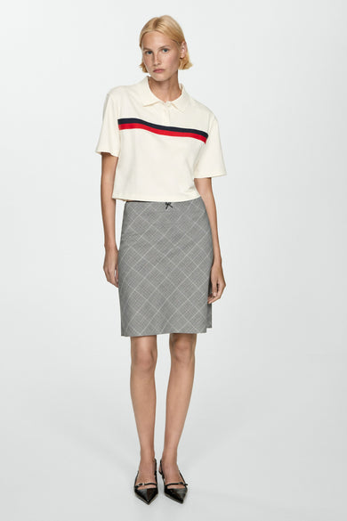 Polo blanc à manches courtes de MANGO, avec des rayures rouges et bleues sur la poitrine.