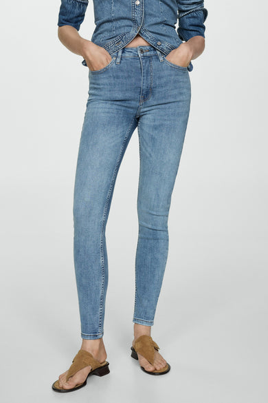 Jean skinny en denim bleu moyen de MANGO, vu de derrière, associé à un chemisier en denim et des mocassins.