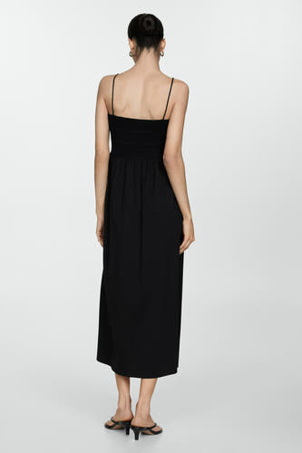 Robe sans manches noire de MANGO, avec un col smock et des fines bretelles, vue de derrière.
