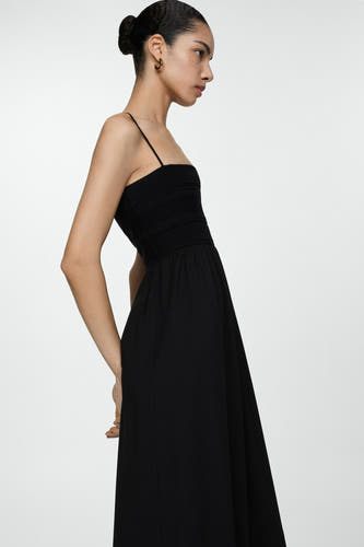 Robe sans manches noire de MANGO, avec des détails smockés en haut et une jupe droite.