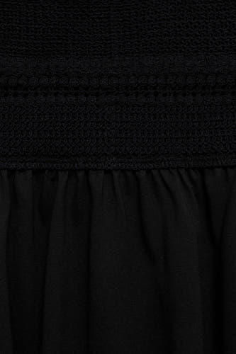 Jupe sans manches noire de MANGO, avec un haut froncé et une jupe plissée.