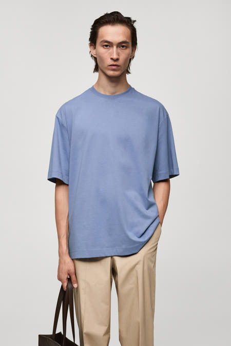 T-shirt bleu marine à manches courtes de MANGO, dos, associé à un pantalon beige et une poche brune.