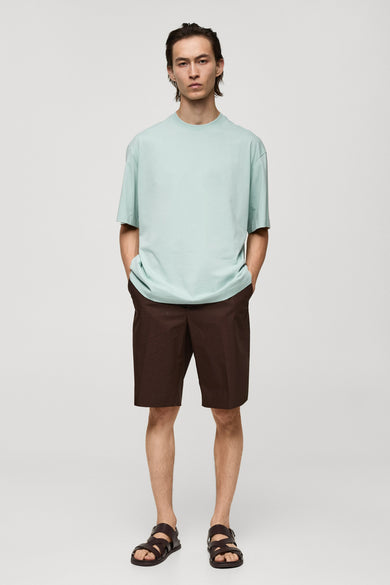 T-shirt bleu à manches courtes de MANGO, associé à des short bruns et des sandales en cuir.