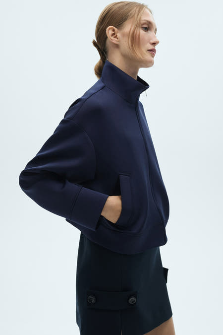 Gilet bleu de MANGO, vu du derrière, combiné avec un minirok et des sandales à talons pointus.
