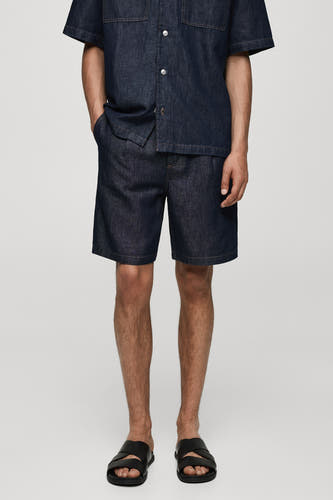 Jean en denim court de MANGO, en bleu moyen, porté avec un t-shirt en denim et des sandales noires.