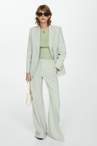 T-shirt vert avec col rond de MANGO, porté sous un blouson et avec une chaîne en or.