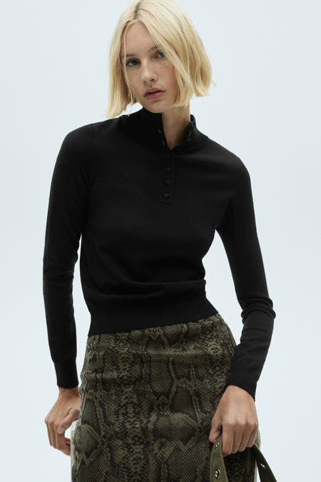 Sweat-shirt multicolore à col rond de MANGO, associé à une jupe avec imprimé serpent et des chaussettes noires à talons.