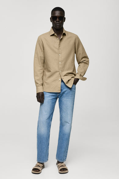 Chemise verte à manches longues de MANGO, portée avec des jeans et des sandales en cuir.