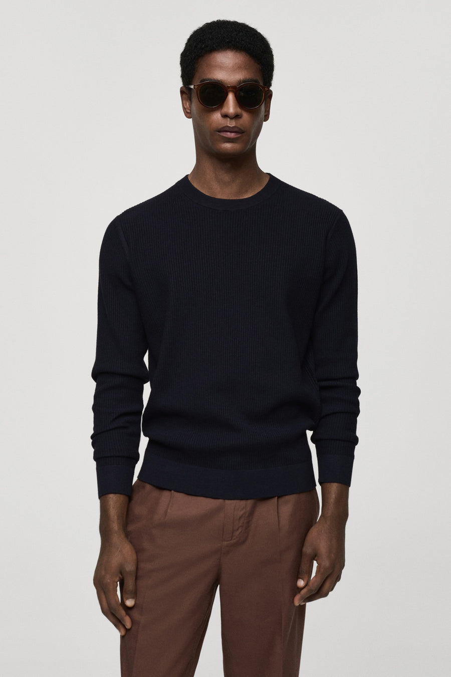 T-shirt bleu avec col rond de MANGO, texture rayée sur le dos, associé à un pantalon marron.