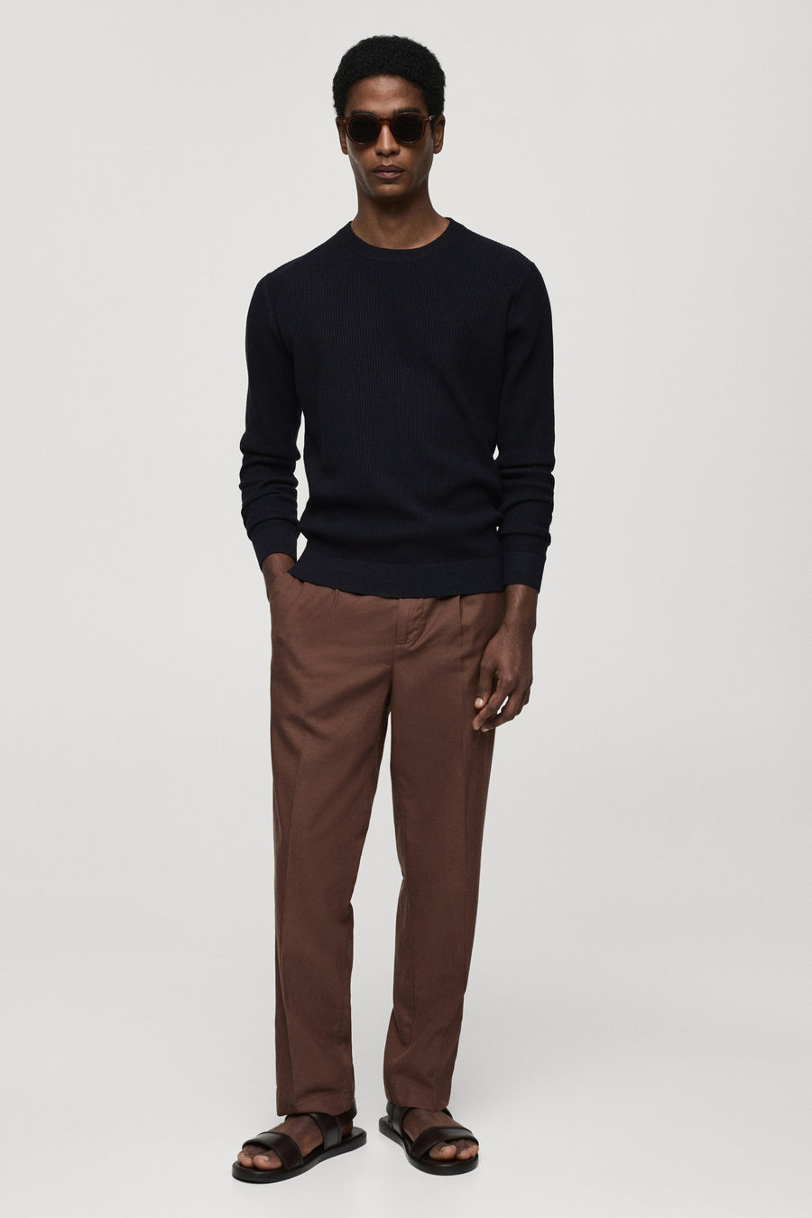 T-shirt bleu avec col rond de MANGO, porté avec un pantalon marron et des sandales.