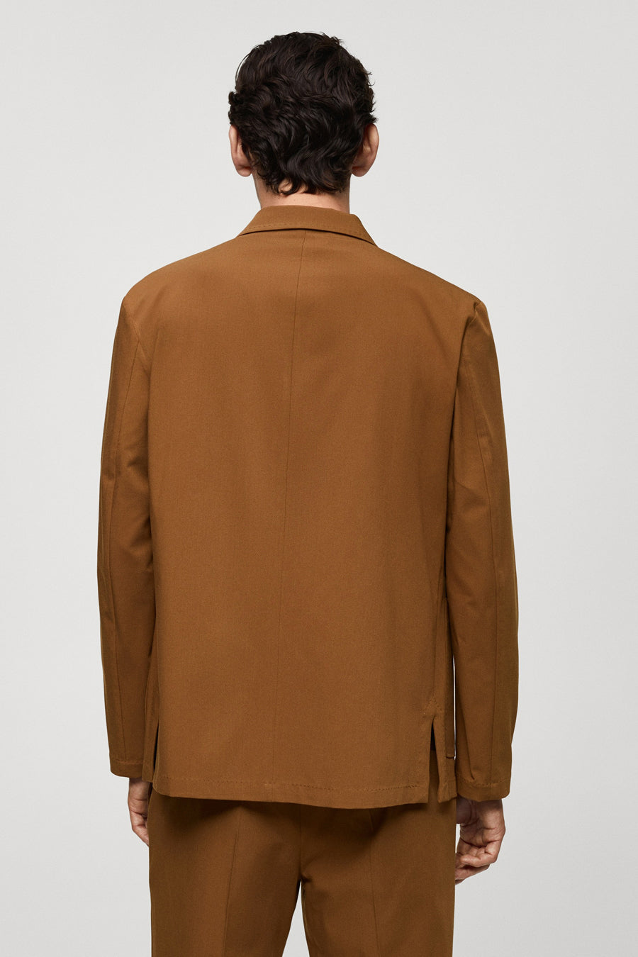 Oranje blazer van MANGO, gezien van achteren, met lange mouwen en een split aan de zijkant.
